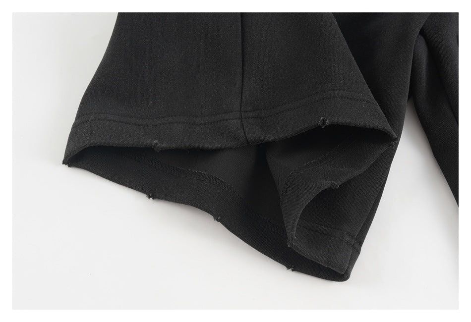 Close-up of a black garment leg opening showing the hem stitching and unfinished distressed edges.