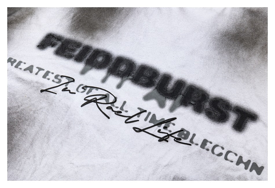 Close-up of dark English lettering and a script graphic printed on the white tie-dye shirt.