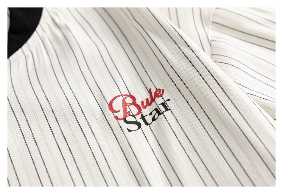 Close-up of an ivory garment with thin dark pinstripes and a red-and-black Bull Star chest graphic.
