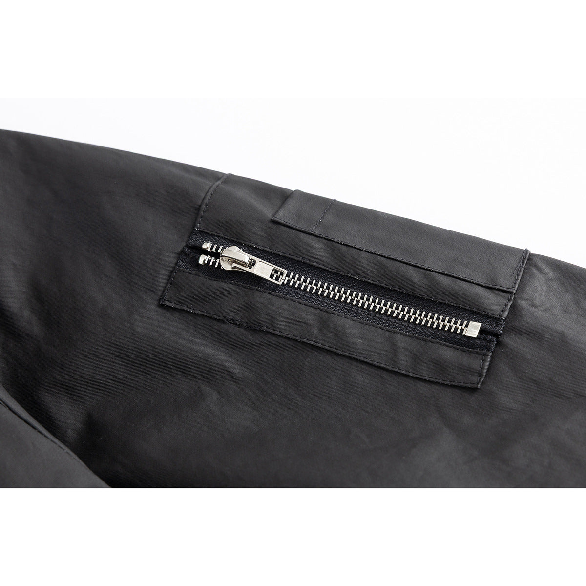 Close-up of a black jacket's silver horizontal zip pocket and stitched flap.