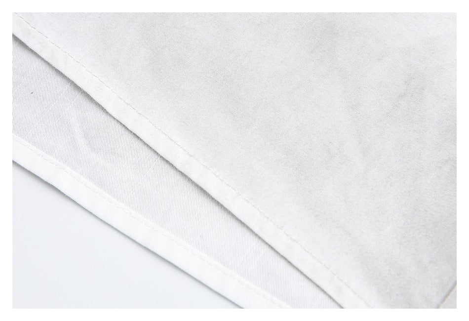 Close-up of a folded white garment hem with visible stitching.