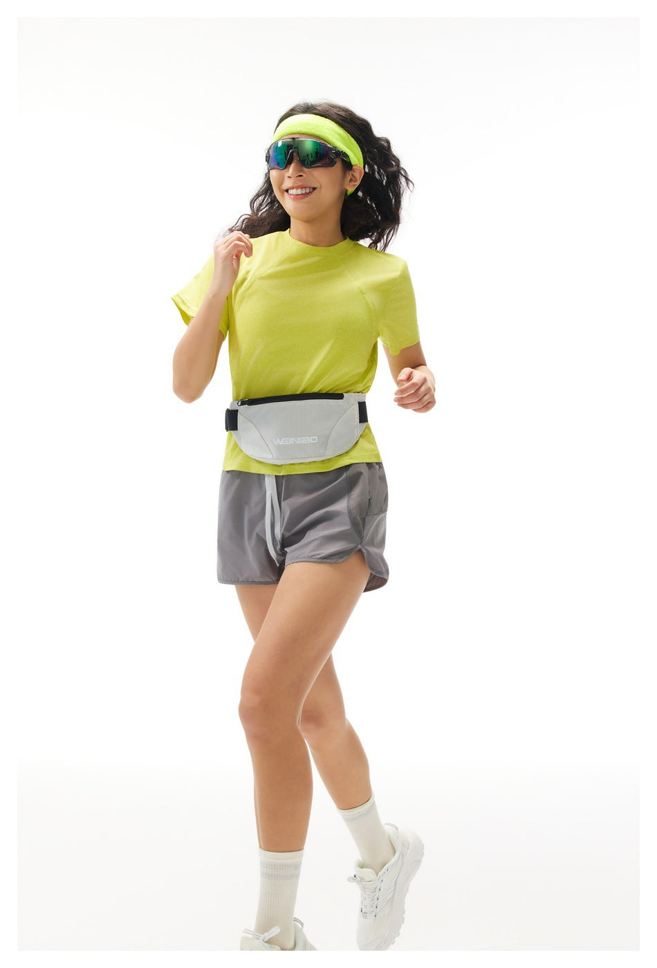 Model running in a lime short-sleeve shirt, gray shorts, and a light waist pack.