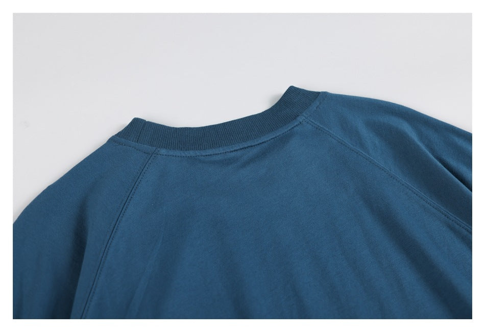 Cropped back view of a blue sweatshirt laid flat, showing the ribbed neckline and raglan seams.