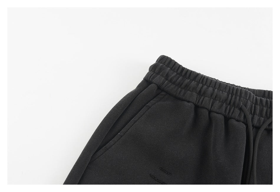 Close-up of black jogger pants showing the elastic waistband, drawstring, and slanted pocket.
