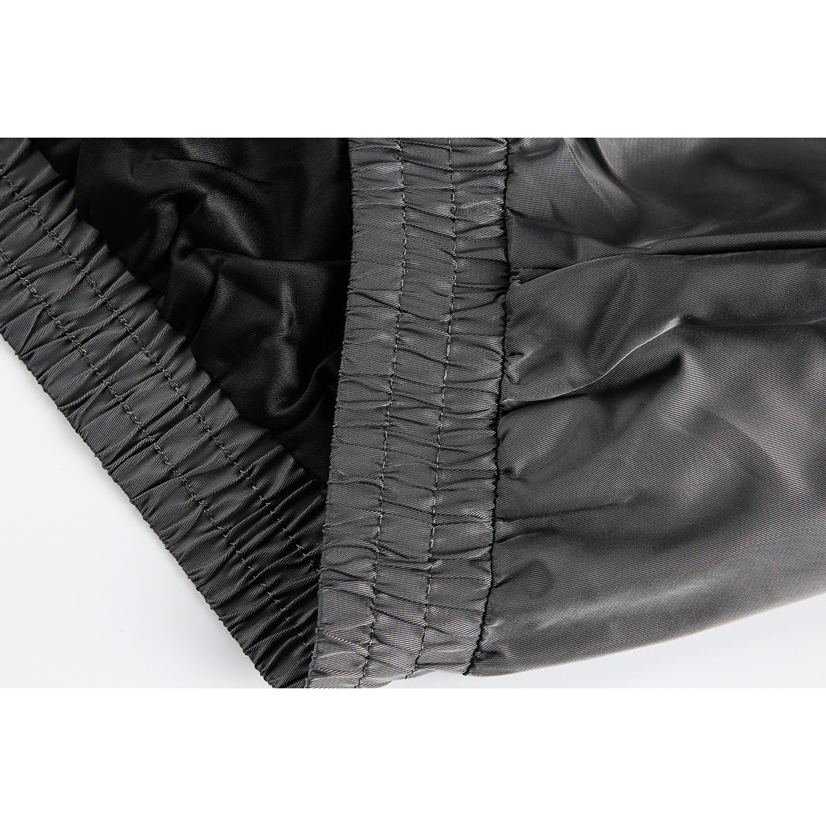 Close-up of a dark jacket's gathered elastic hem and stitched seam.