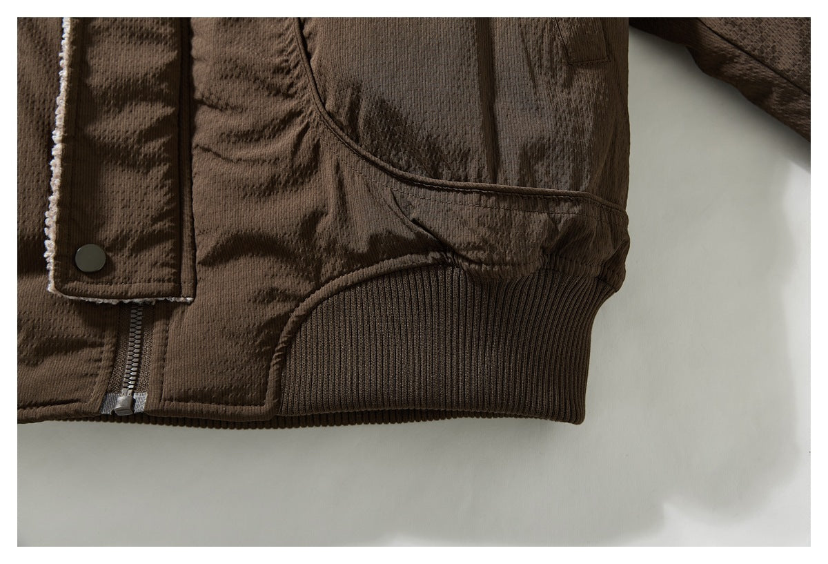 Close-up of the brown jacket's ribbed hem, lower snap placket, and curved pocket seam.