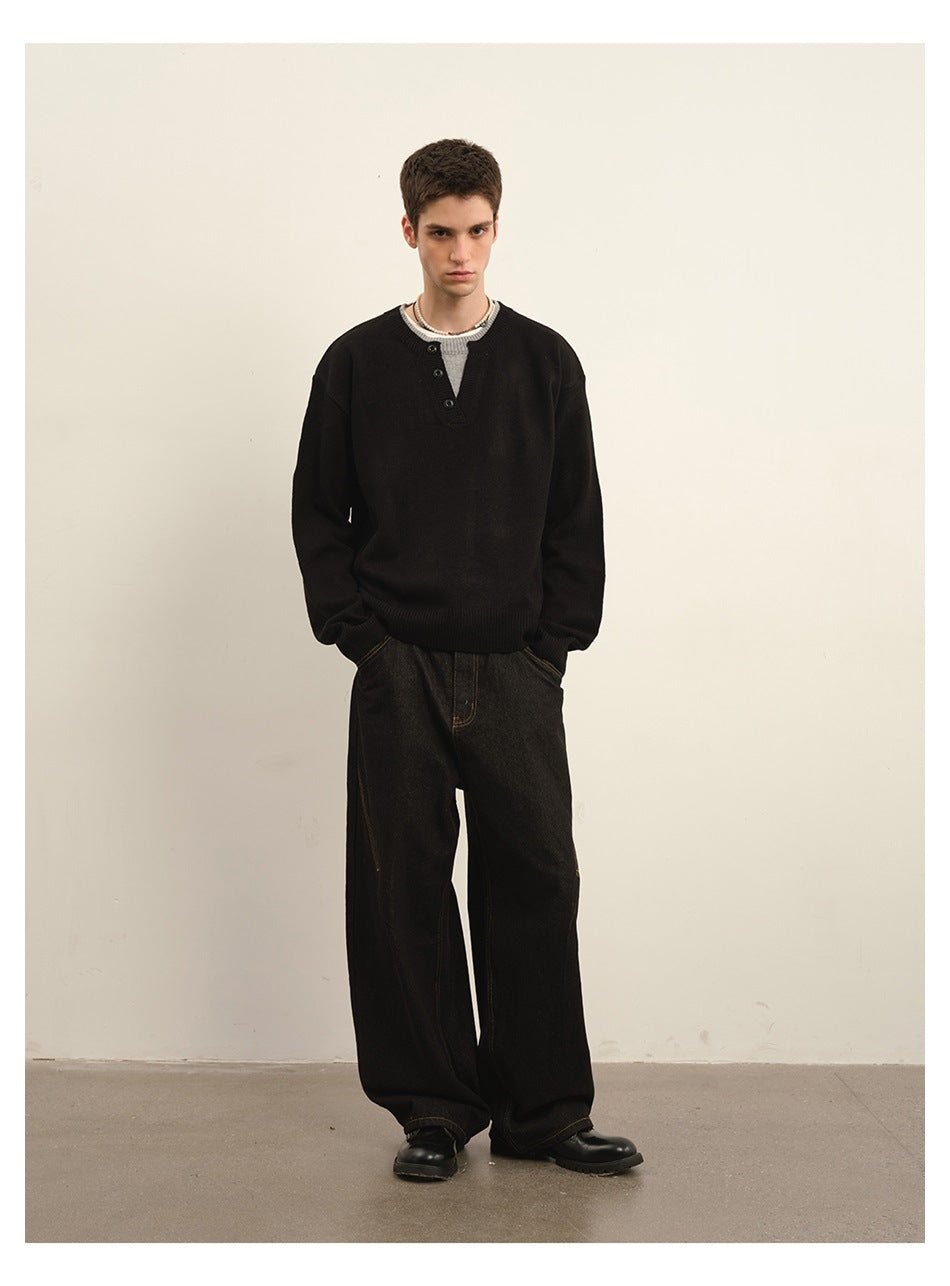 Front view of a model wearing a black button-neck sweater with dark wide-leg trousers.
