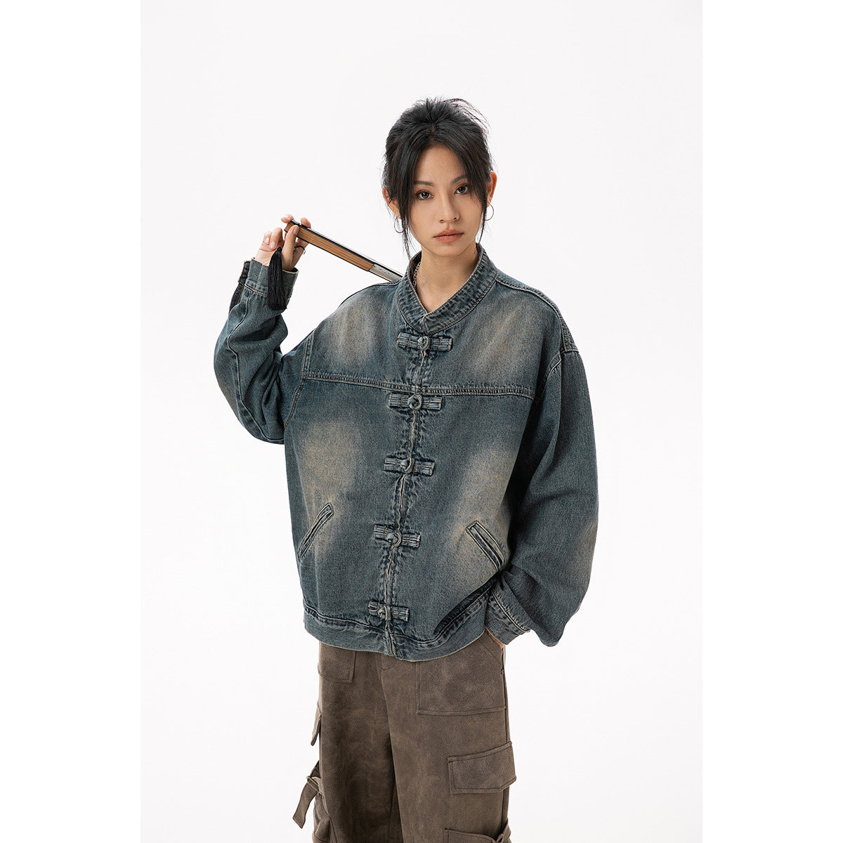 Model wearing a faded blue-gray denim jacket with a stand collar, frog closures, and angled pockets.