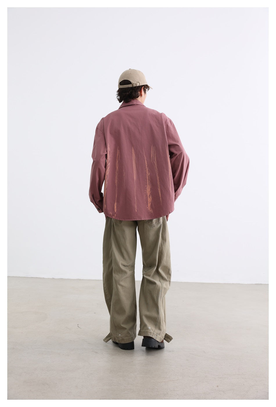 Rear view of a model wearing a dusty rose shirt with tan brushstroke graphics and khaki trousers.