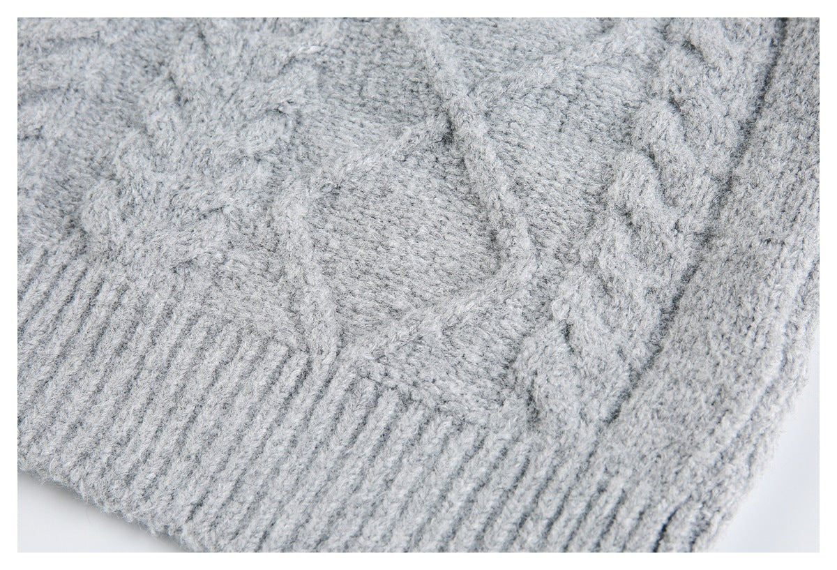 Close-up of light gray knit fabric showing a ribbed edge and textured stitches.
