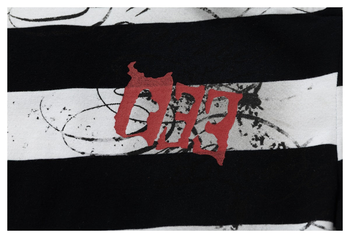 Close-up of a black-and-white striped garment with distressed graphics and a red printed design.
