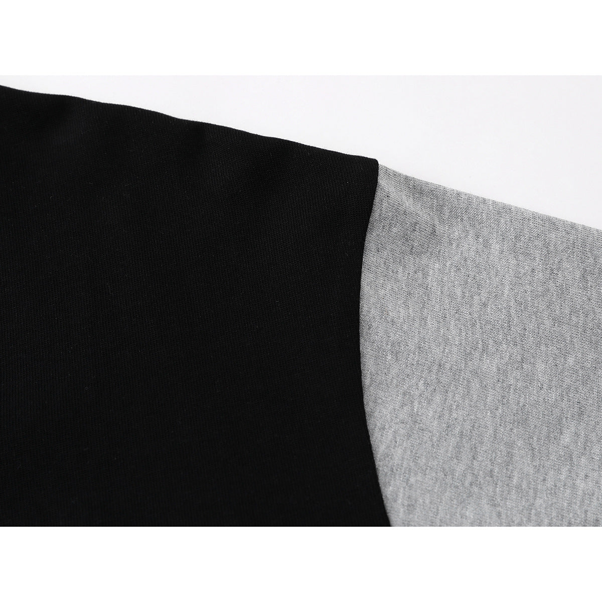 Close-up of the seam between the black upper panel and heather-gray sleeve of a color-block shirt.