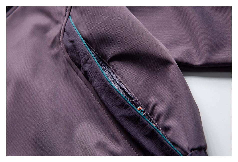 Close-up of a plum jacket sleeve showing a diagonal zippered pocket with teal piping and a colorful pull.