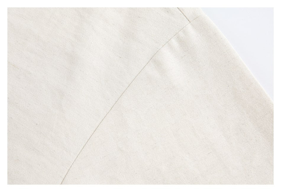 Close-up of a diagonal stitched seam on off-white textured garment fabric.