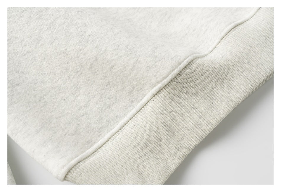 Close-up of the light heather gray sweatshirt's ribbed waistband and hem seam.