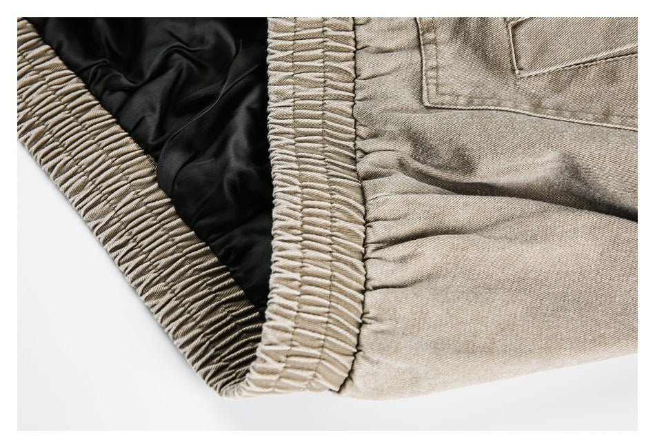 Close-up of a gathered elastic waistband with black inner lining on beige-tan pants.