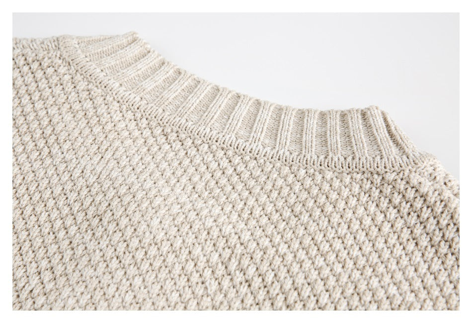 Close-up of the cream sweater's ribbed neckline and textured knit body.