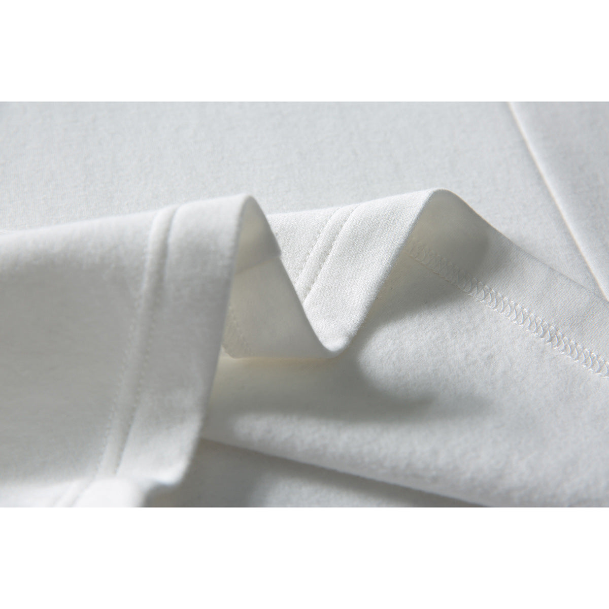Close-up of a white sweatshirt seam and folded edge with visible stitching.