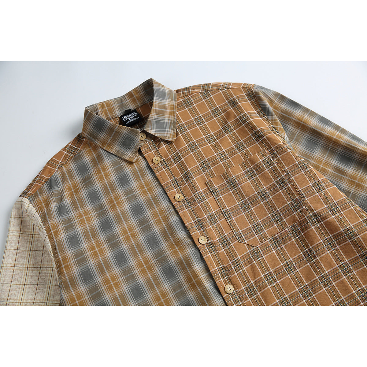 Close-up of a flat-lay long-sleeve shirt with brown, gray and cream plaid, button front and chest pocket.