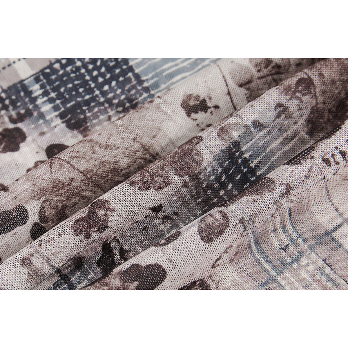 Close-up of textured shirt fabric with an abstract brown, gray, and blue print, shown in soft folds.