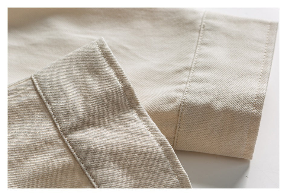 Close-up of a cream shirt sleeve cuff and adjoining seam, showing the stitching and fabric texture.