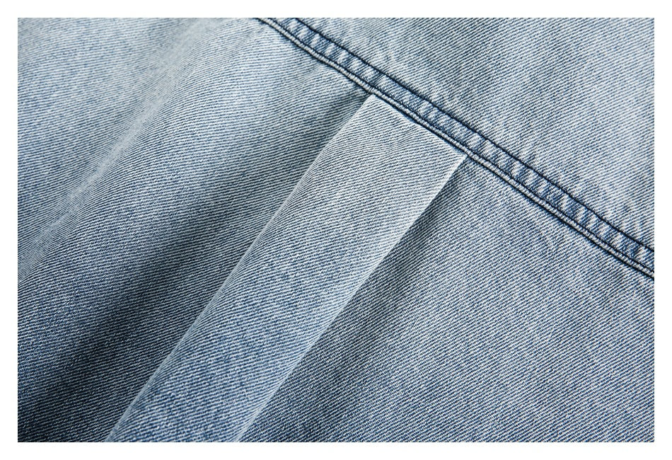 Close-up of overlapping light blue denim panels and a diagonal stitched seam.