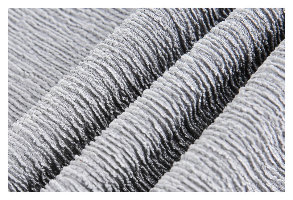 Extreme close-up of light gray ribbed fabric gathered into raised folds.