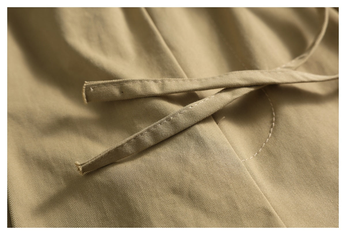 Close-up of two narrow tan waist ties resting across the matching garment fabric.