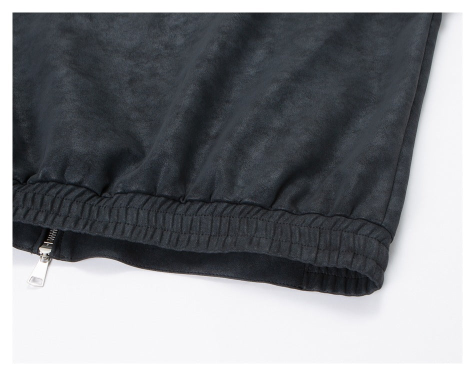 Close-up of the jacket's gathered elastic hem and lower zipper on dark charcoal fabric.