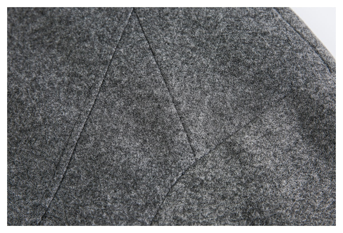 Close-up of charcoal gray textured garment fabric with a diagonal seam.