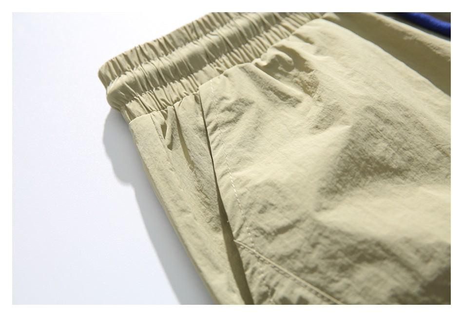 Close-up of the pale khaki shorts' elastic waistband and stitched side pocket seam.