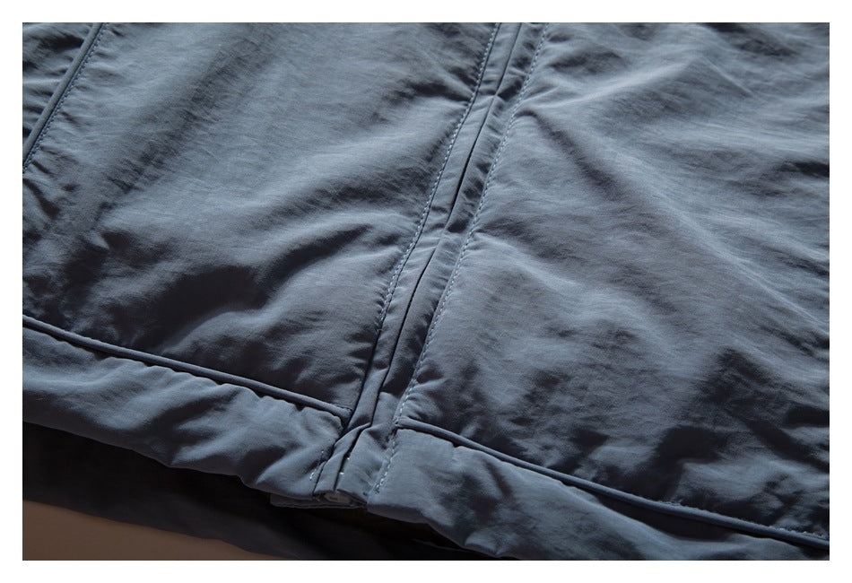 Close-up of a blue-gray jacket hem with stitched seams and narrow piping.