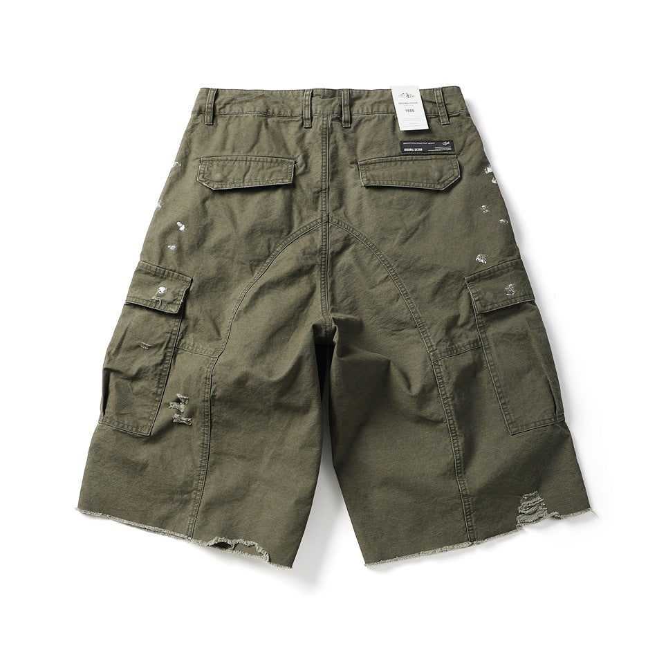 Back view of olive cargo shorts with flap pockets, distressed details, and raw hems.