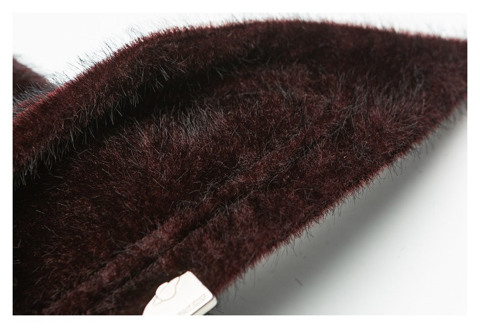 Close-up of a dark burgundy plush garment edge with a small metal plaque.