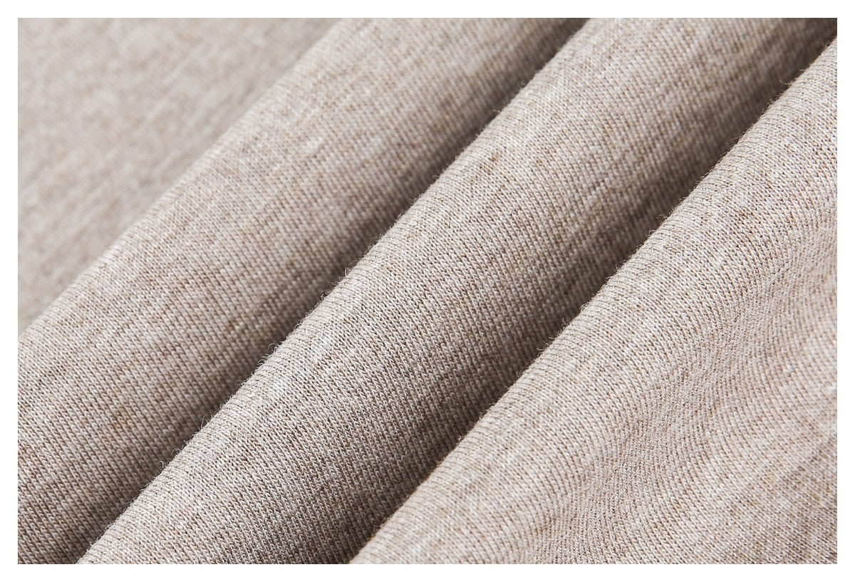 Close-up of beige heather knit fabric draped in folds, showing its surface texture.