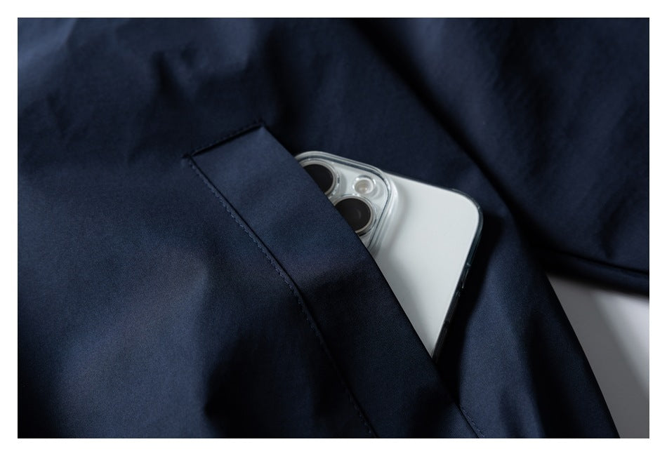 Close-up of a navy jacket pocket holding a white smartphone.