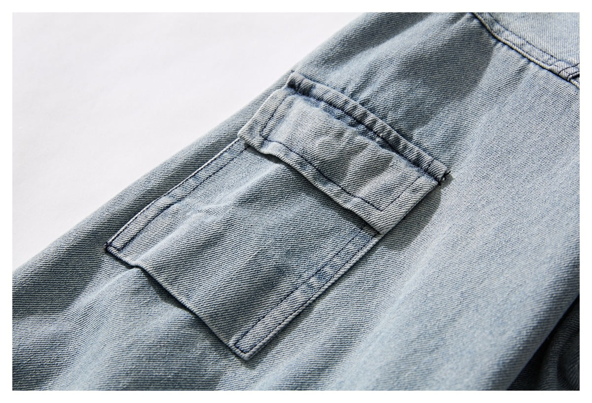 Close-up of a flap chest pocket on a light blue washed denim jacket.