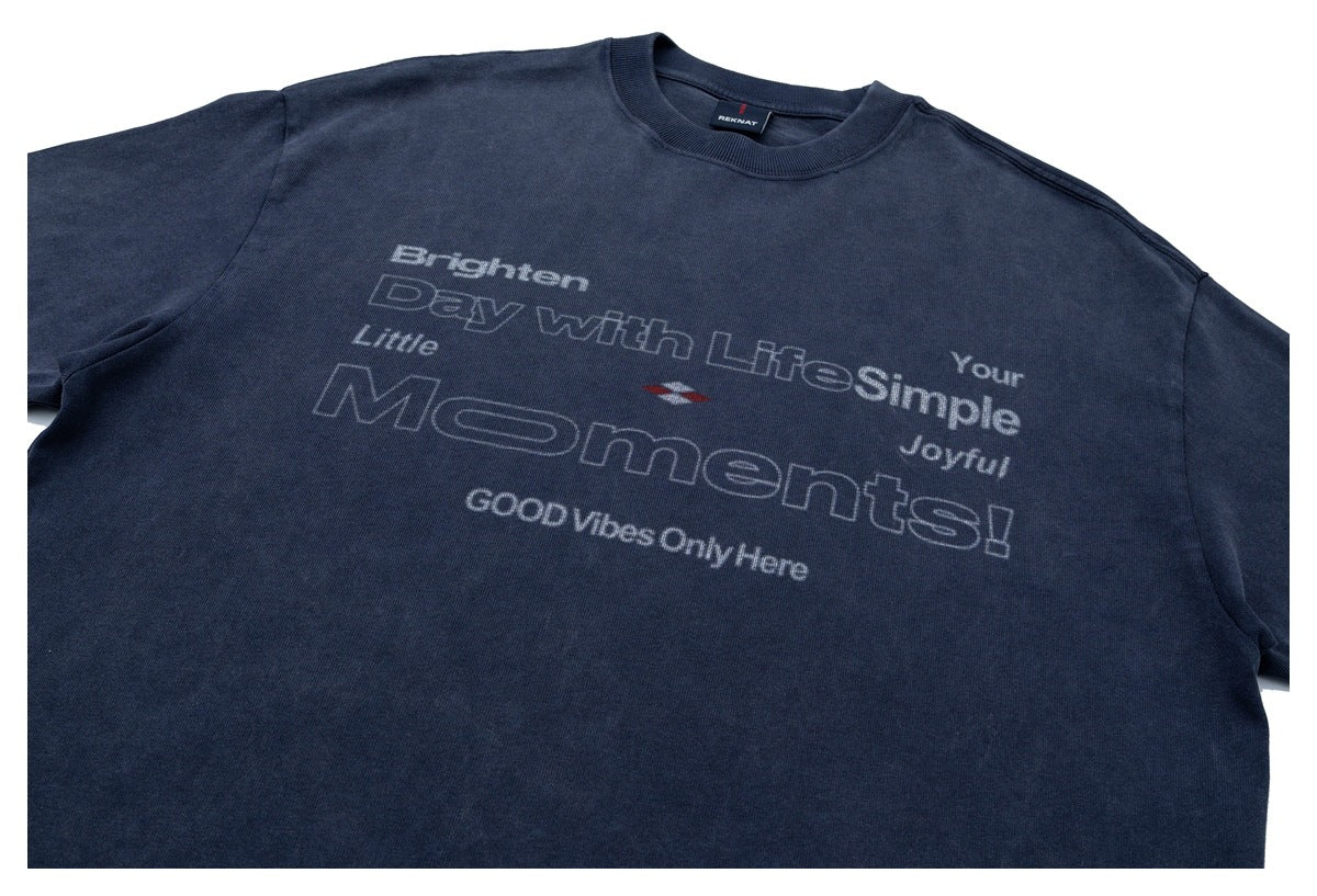 Angled front view of a navy crew-neck T-shirt with short sleeves and a large light-colored English slogan graphic.