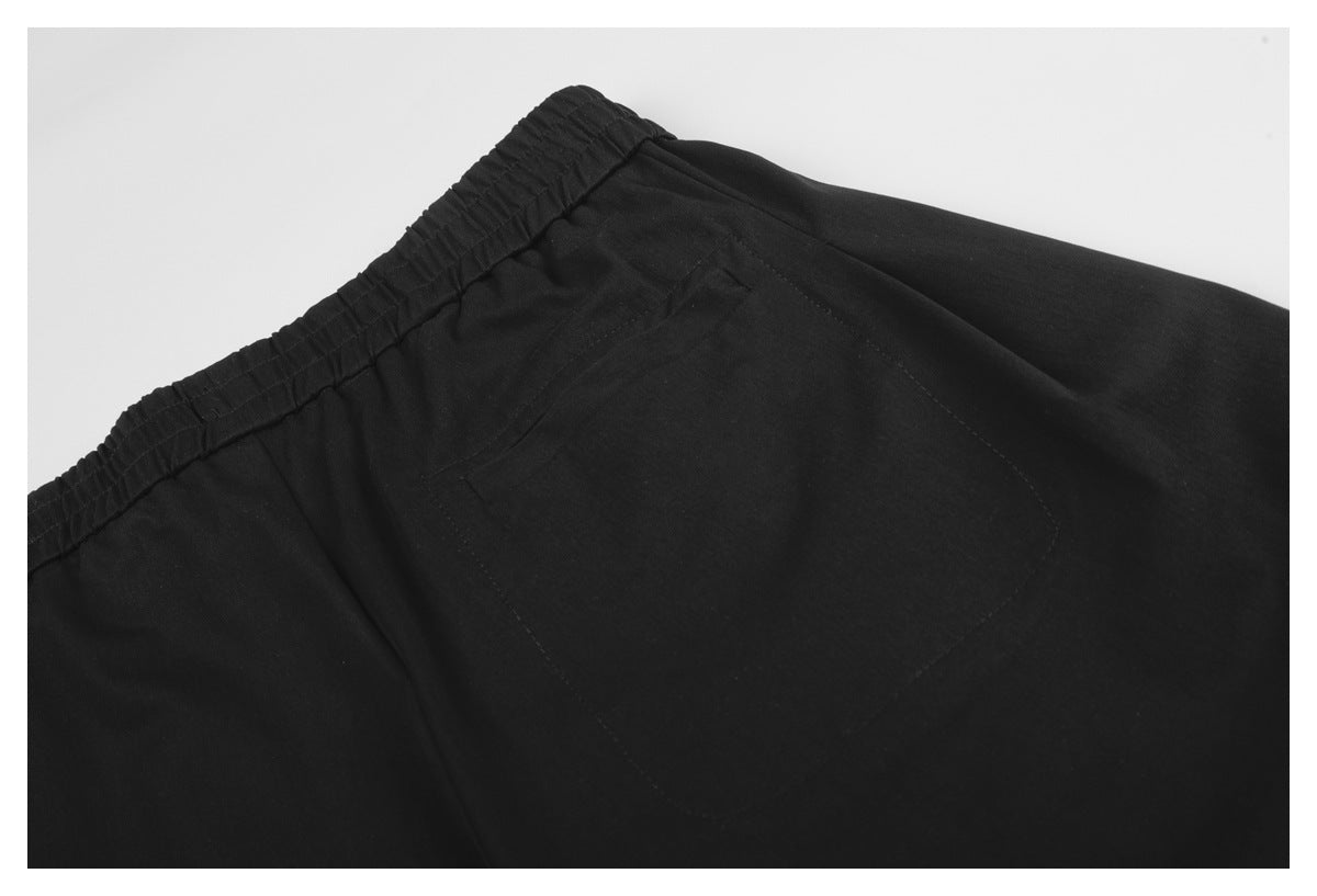 Close-up of a stitched rear pocket and elastic waistband on black trousers.