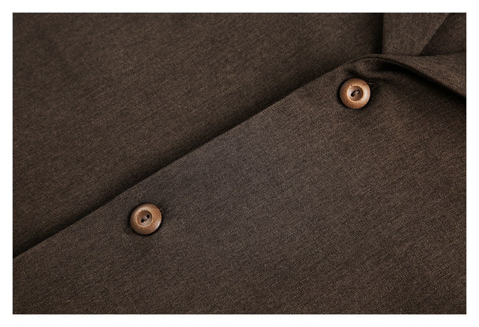 Close-up of a dark brown woven garment with two round brown buttons and overlapping fabric panels.