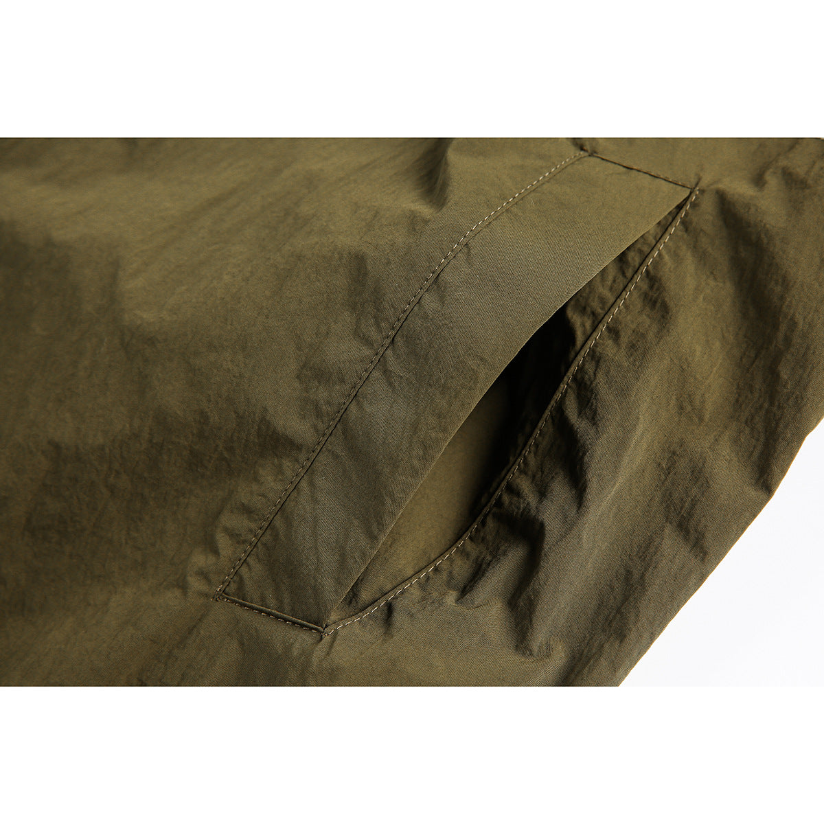 Close-up of an olive jacket pocket opening and stitched fabric panel.