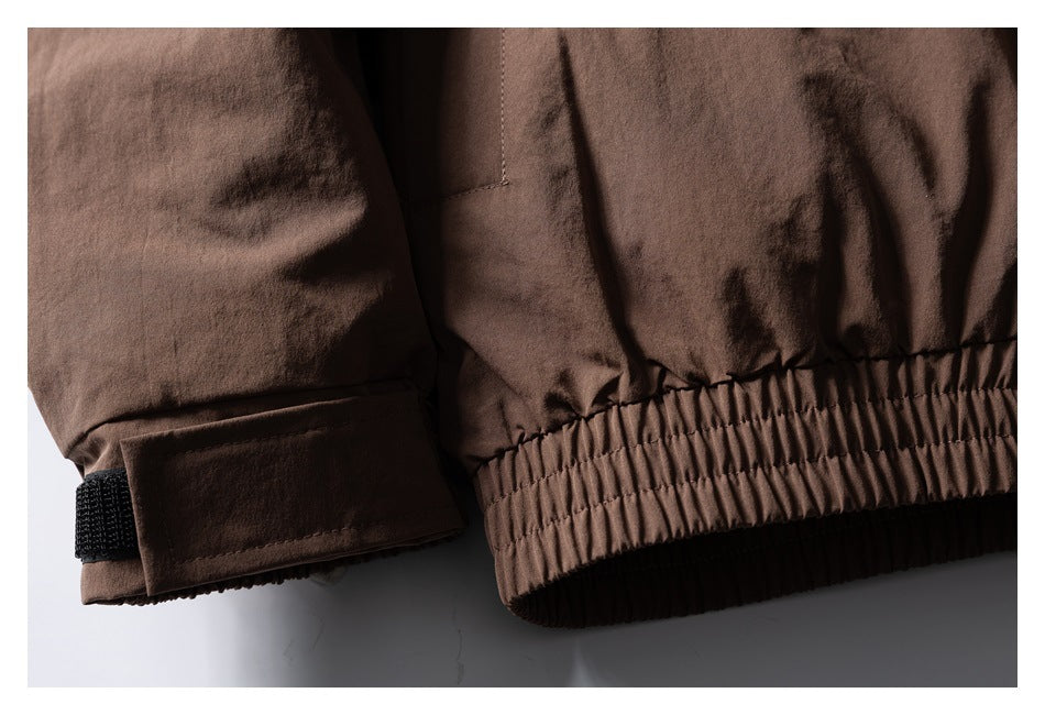 Close-up of a brown jacket cuff with a black hook-and-loop tab and gathered elastic hem.