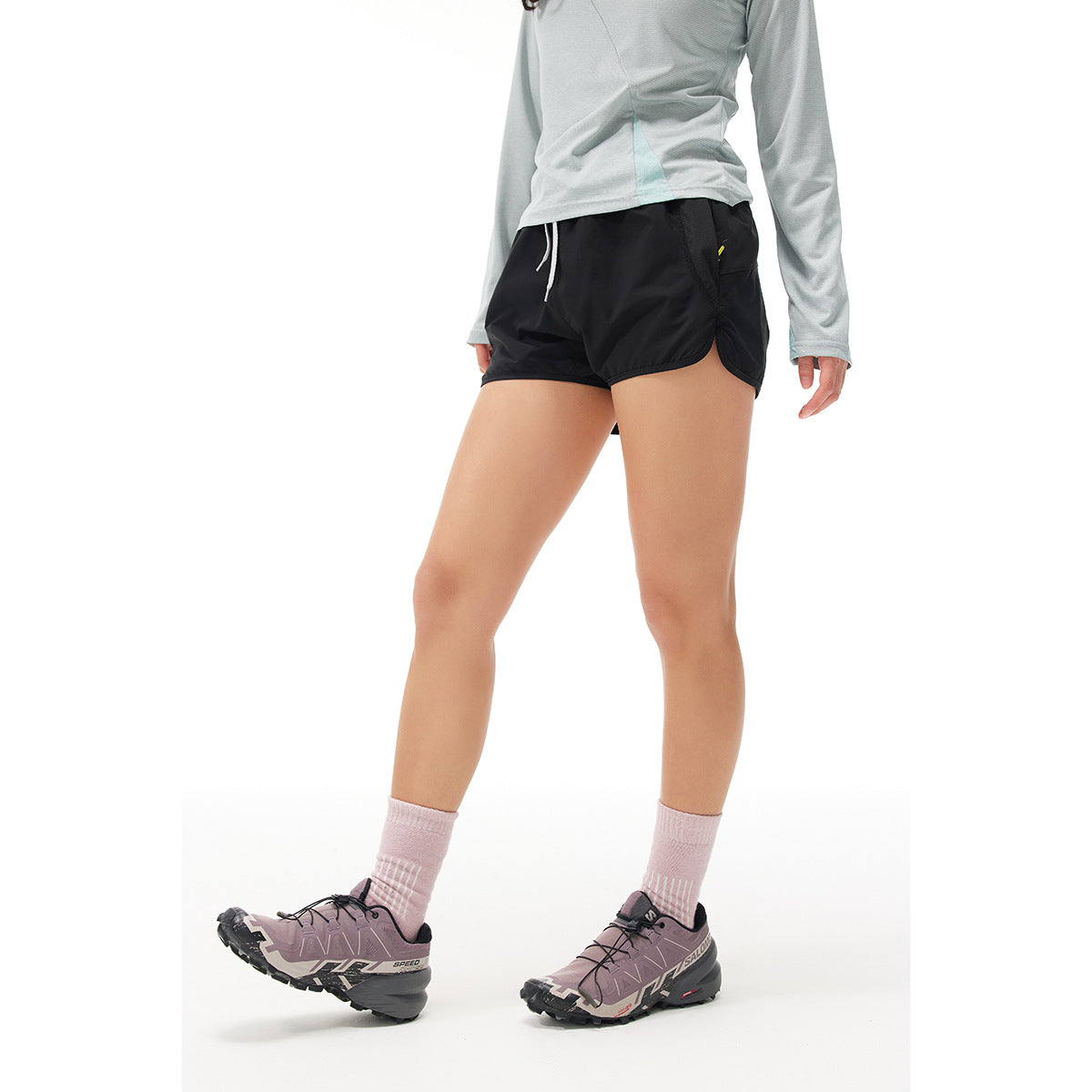 Front view of a model wearing black running shorts with a white drawstring and curved hems.
