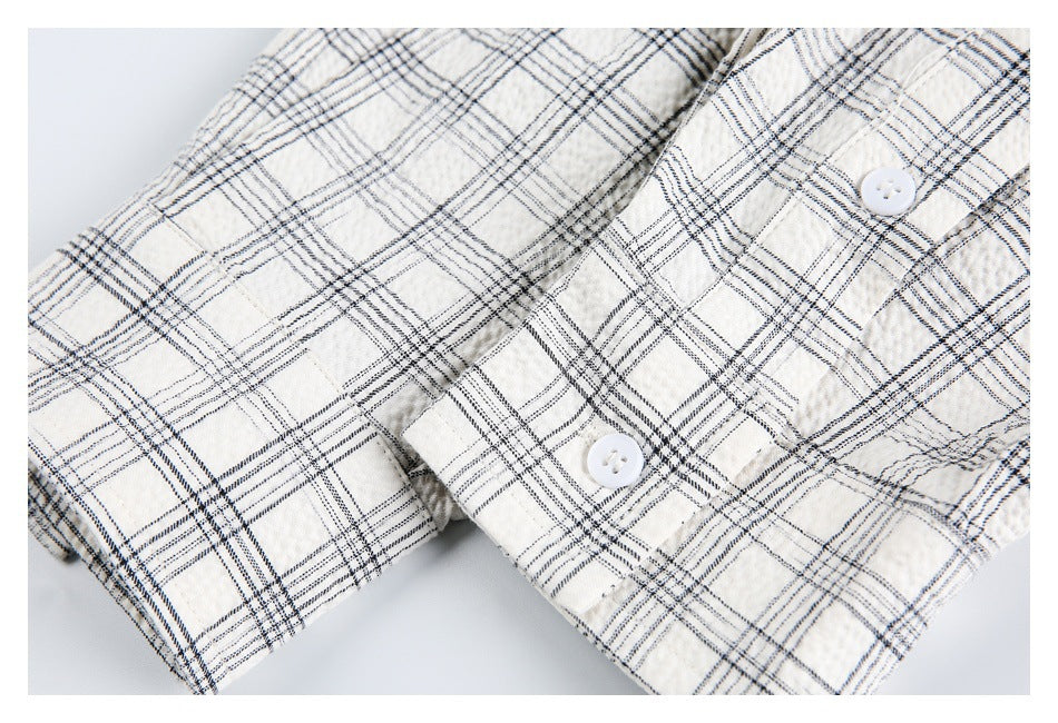 Close-up of an off-white plaid garment with two white buttons and stitched edges.