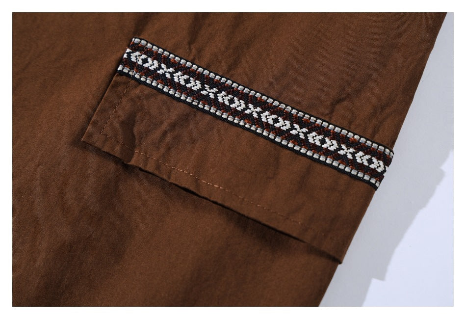 Close-up of a brown shirt sleeve cuff with a band of black, white, and brown geometric trim.