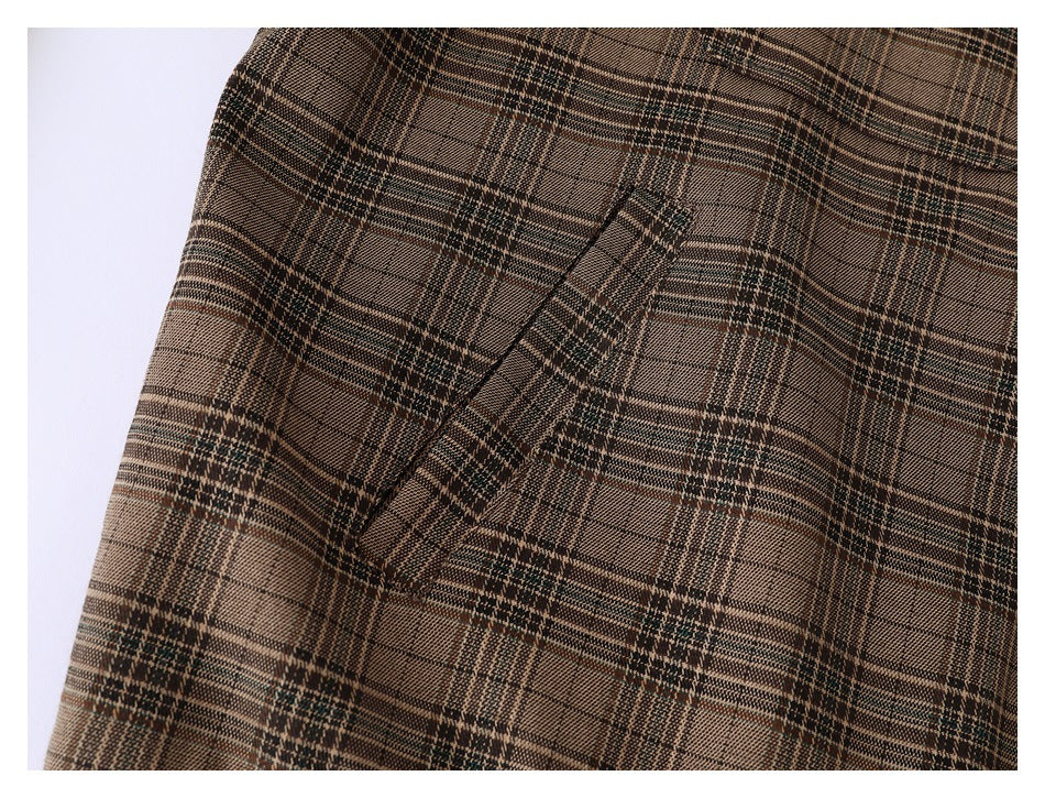 Close-up of a slanted welt pocket on a brown plaid jacket.