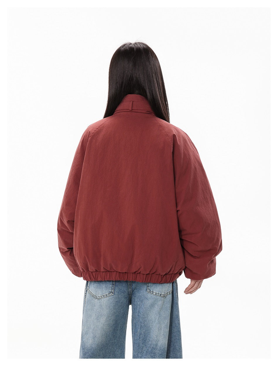 Rear view of the rust-red jacket on a model, showing its plain back and elasticated hem.