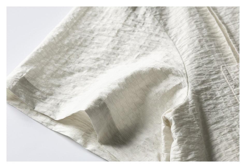 Close-up of pale ivory textured fabric with a curved seam and folded edge.