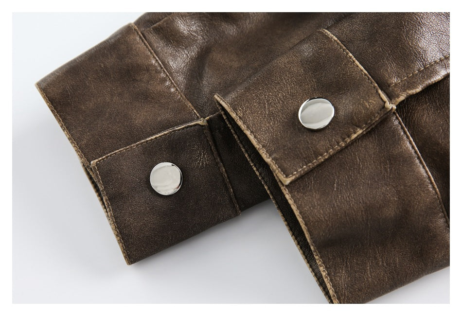 Close-up of a dark brown jacket cuff with two round silver snap buttons and contrast edge stitching.