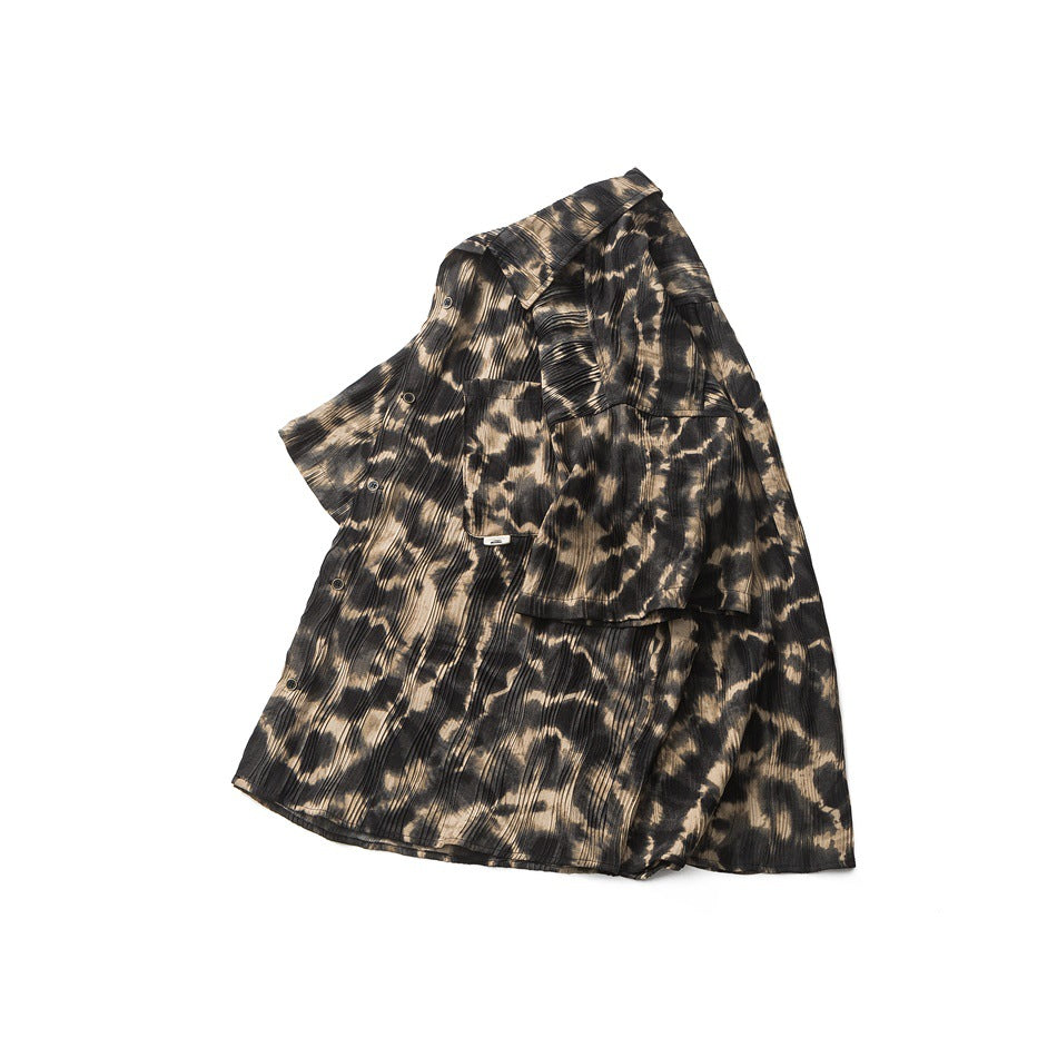 Front view of a button-up shirt with a collar, chest pocket, and black and tan abstract pattern.